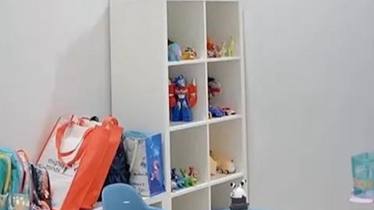 Ruang bermain anak-anak rapi, ada mainan di rak, rak buku, dan meja tulis.