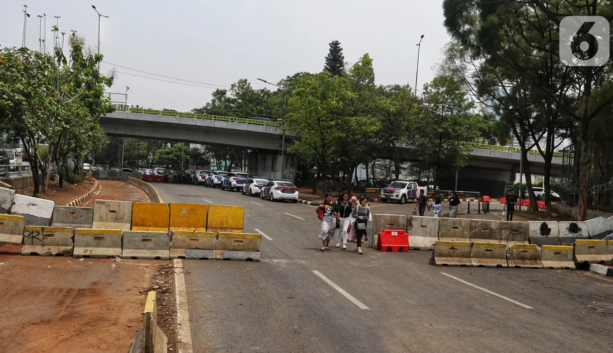 Warga berjalan dekat road barrier beton yang dipasang di sekitar Gedung DPR RI, Jakarta, Kamis (17/10/2019). Polisi kembali menutup sejumlah ruas jalan menuju kawasan Gedung DPR RI guna menjaga kondusifitas jelang pelantikan Presiden dan Wakil Presiden terpilih. (Liputan6.com/JohanTallo)