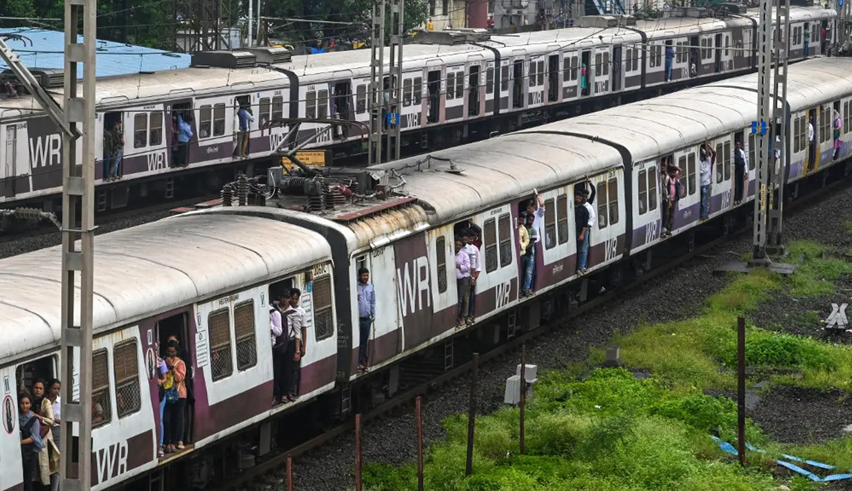 Penumpang berdiri pada pintu gerbong kereta yang terbuka saat mereka melakukan perjalanan dengan kereta lokal di Mumbai, India, Kamis (8/9/2022). (Indranil MUKHERJEE/AFP)