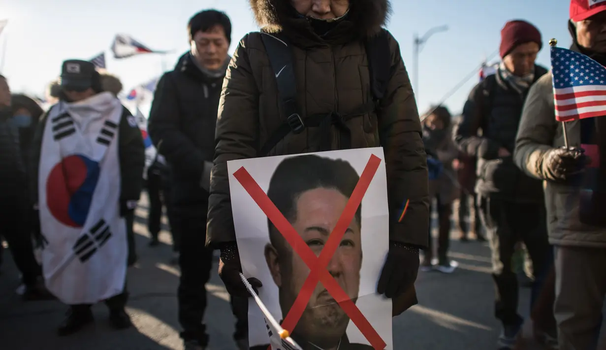 Pengunjuk rasa anti-Korea Utara membawa poster Kim Jong-Un saat menggelar aksi di pelabuhan Mukho di Donghae, Korea Selatan (6/2). (AFP/Ed Jones)