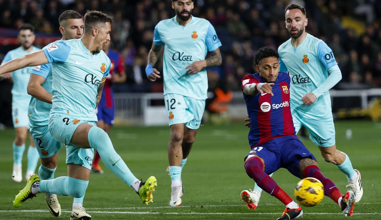 Striker Barcelona, Raphinha (kanan) melepaskan tendangan yang berusaha diblok bek Mallorca, Antonio Raillo (kiri) pada laga pekan ke-28 LaLiga 2023/2024 yang berlangsung di Olimpic Lluis Companys Stadium, Barcelona, Sabtu (9/3/2024) dini hari WIB. (AP Photo/Joan Monfort)