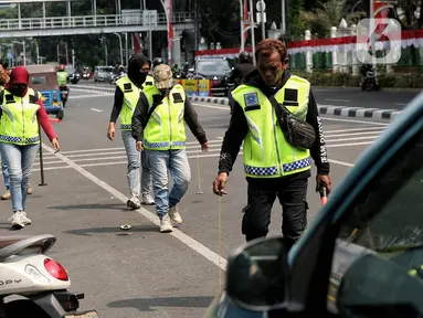 Relawan dari komunitas sapu bersih (saber) ranjau paku menyisir rute yang akan dilewati Pemimpin Gereja Katolik Dunia Paus Fransiskus, Rabu (4/9/2024). (Liputan6.com/Angga Yuniar)