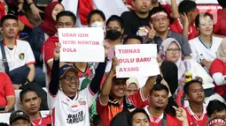 Pendukung timnas Indonesia membentang kertas tulisan saat menyaksikan laga kualifikasi Grup A Piala AFF 2022 antara Indonesia melawan Kamboja di di Stadion Utama Gelora Bung Karno, Jakarta, Jumat (23/12/2022). Indonesia unggul 2-1 atas Kamboja lewat gol yang dicetak Egy Maulana Vikry dan Witan Sulaeman. (Liputan6.com/Helmi Fithriansyah)