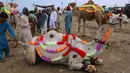 Penjual berinteraksi dengan pembeli di dekat untaunya yang dihias di pasar ternak untuk Idul Adha di Islamabad, Pakistan, Minggu (26/7/2020). Para pedagang menghias unta agar hewan kurban yang dijualnya dilirik pembeli. (AP Photo/Anjum Naveed)