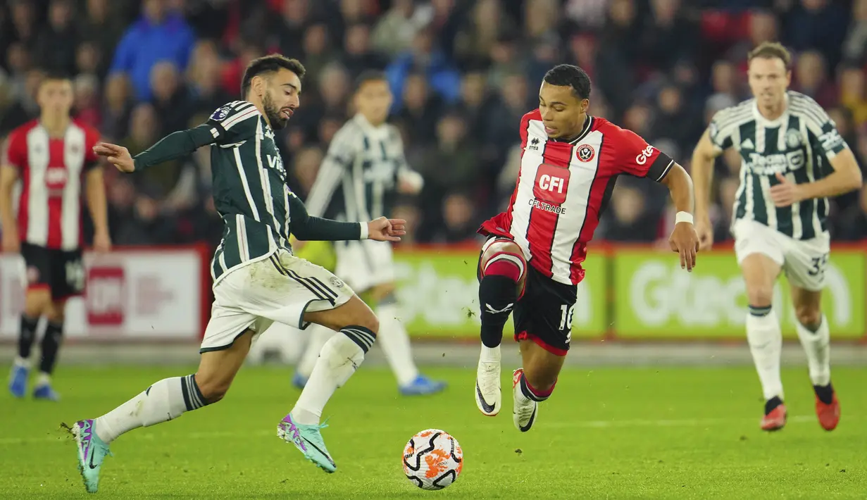 Pemain MU, Bruno Fernandes (kiri), dan pemain Sheffield United, Cameron Archer, berusaha merebut bola dalam laga pekan ke-9 Premier League 2023/2024 yang berlangsung di Bramall Lane, Inggris, Minggu (22/10/2023). (AP Photo/Jon Super)