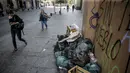 Orang-orang berjalan melewati tumpukan sampah yang diakibatkan pemogokan petugas sampah di Santiago (14/11/2019). Protes kekerasan meletus di ibukota Chile, Santiago, pada Selasa ketika mata uang negara itu turun ke level terendah dalam sejarah. (AFP/Javier Torres)