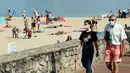 Orang-orang memakai masker berjalan di sepanjang pantai di Saint Jean de Luz, Prancis barat daya, Selasa (27/7/2021). Otoritas setempat di Prancis memberlakukan kembali mandat masker dan pembatasan COVID-19 lainnya karena penyebaran varian delta menyebabkan rawat inap meningkat lagi. (AP/Bob Edme)