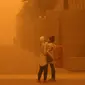 Perempuan mengambil video dengan smartphone mereka di tengah badai debu parah di Kuwait City pada 23 Mei 2022. Kabut oranye tebal telah menyelimuti Kuwait pada hari Senin, menyebabkan penerbangan ke dan dari bandara internasional negara itu ditangguhkan sementara, kata regulator penerbangan sipil. (Yasser Al-Zayyat / AFP)