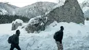 Imigran berjalan melintasi jalan yang dipenuhi salju untuk menuju perbatasan antara Italia dan Prancis di Pegunungan Alpen, Italia (13/1). Bahkan mereka melintasi salju pegunungan Alpen dengan pakain biasa bukan pakain untuk di Salju.(AFP/Piero Cruciatti)