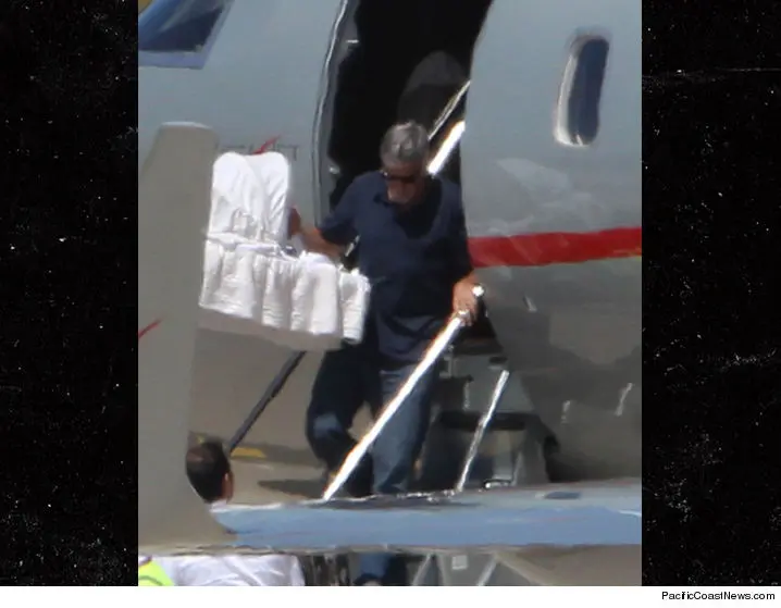 George Clooney saat turun dari pesawat bersama bayinya. (TMZ)