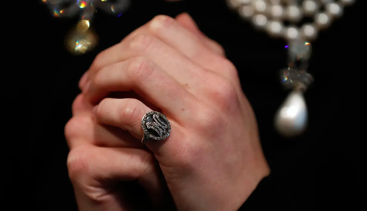 Foto pada 19 Oktober 2018, model mengenakan cincin monogram mendiang Ratu Prancis, Marie Antoinette di Sotheby, London. Cincin itu memuat seikat rambut Ratu Marie dan termasuk perhiasan yang dilelang di Jenewa pada 14 November 2018. (AP/Frank Augstein)