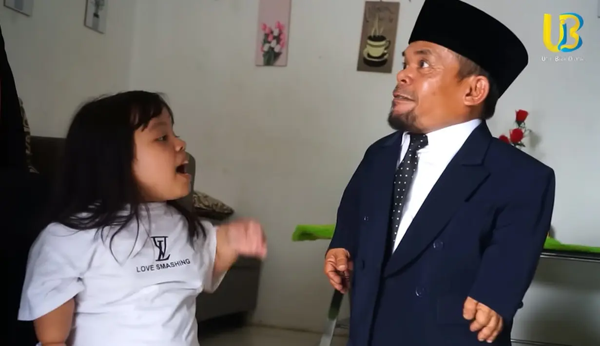 Penampilannya siap untuk berangkat dampingi putranya wisuda. Ucok Baba tampil mengenakan setelan jaz warna biru dongker dan peci. [Youtube/Ucok Baba official]