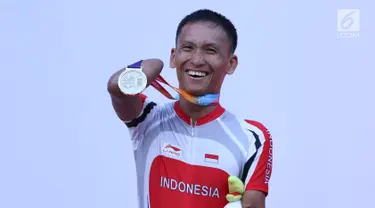 Atlet ParaCycling, Anwar Saipul memperlihatkan medali perak nomor Mens C3 Individual Time Trial Road Race Asian Para Games 2018 usai prosesi pengalungan medali di Sirkuit Sentul, Bogor, Senin (8/10). (Liputan6.com/Helmi Fithriansyah)