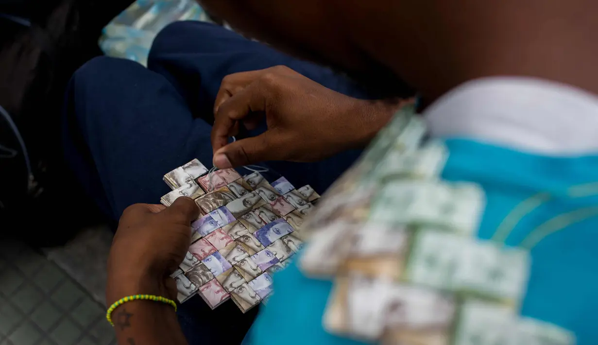 Wilmer Rojas (25) saat membuat tas dari lembaran mata uang Bolivar di Caracas, Venezuela, 30 Januari 2018. Inflasi yang tinggi membuat mata uang tersebut terus kehilangan nilainya. (AFP Photo/Federico Parra)