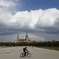 Seorang pengendara sepeda melintasi area Theresienwiese, tempat festival bir 'Oktoberfest' diadakan, di depan gereja St. Pauls di Munich, Senin (3/5/2021). Jerman kembali membatalkan festival bir Oktoberfest untuk tahun kedua karena pandemi covid-19. (AP Photo/Matthias Schrader)