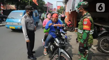 Anggota TNI-Polri menghentikan warga yang tidak mengenakan masker saat razia gabungan Kelurahan Gandul di Perempatan Gandul, Cinere, Depok, Kamis ( 29/08/2020). Razia ditujukan untuk menekan penyebaran Covid-19 dengan memberikan sanksi berupa hukuman fisik dan kerja sosial. (merdeka.com/Arie Basuki)