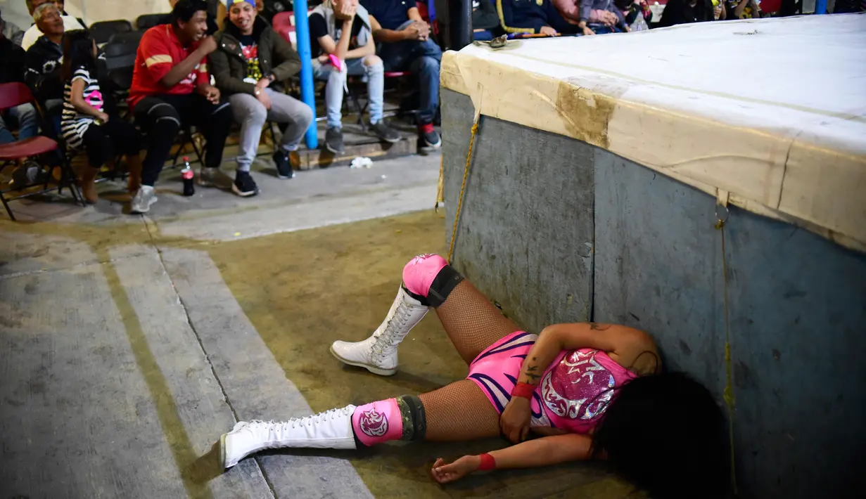 Pegulat wanita Meksiko, Brillo de Luna (kiri) terjatuh dari ring saat tampil di 2 de Junio Arena di Ciudad Nezahualcoyotl, Negara Bagian Meksiko, Minggu (4/2). (Pedro PARDO/AFP)