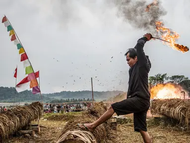 Seorang peserta menyalakan meriam yang terbuat dari batang pohon dengan menggunakan karbit dan air untuk menciptakan suara ledakan selama Festival Kuluwung, di Sukasirna, Jawa Barat, pada tanggal 5 April 2025. (ADITYA AJI/AFP)