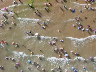 Wisatawan mendinginkan diri sambil bermain di sebuah pantai di Qingdao, China timur, pada 3 Agustus 2019. Banyak warga di Negeri Tirai Bambu memanfaatkan musim panas dengan mengunjungi pantai untuk mengisi liburan. (Photo by FRED DUFOUR / AFP)