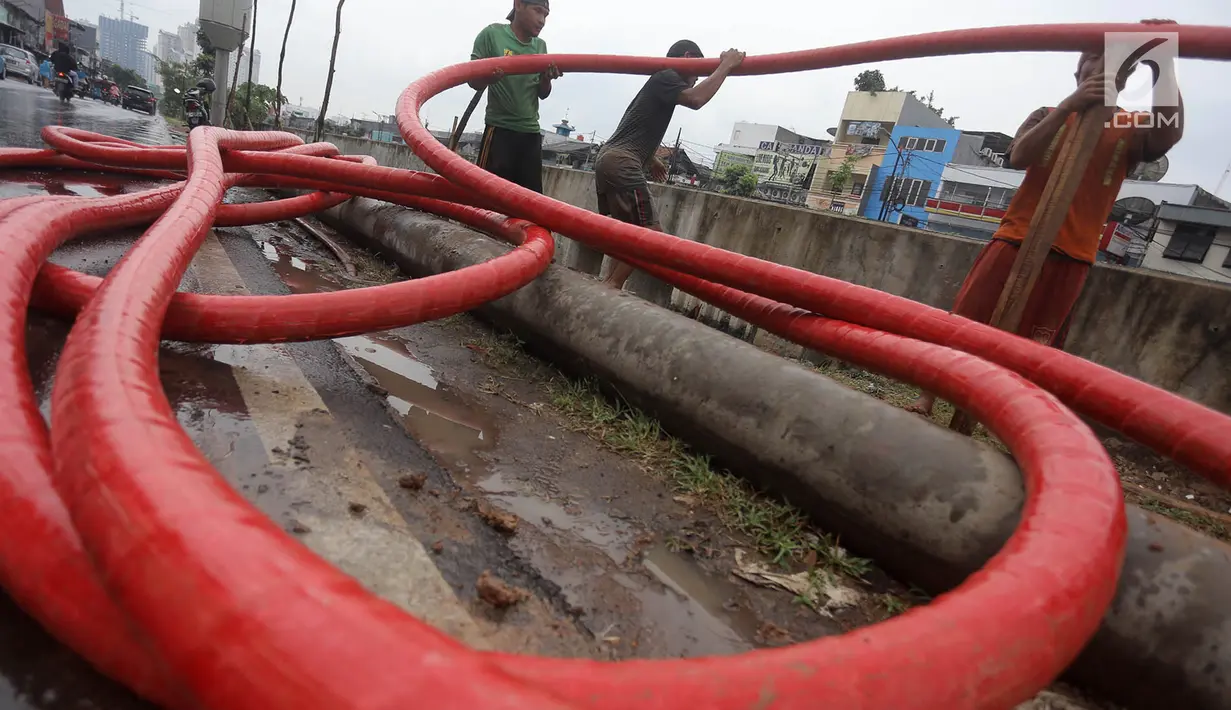 Pekerja merapikan kabel jaringan utilitas ke dalam tanah di kawasan Kemayoran, Jakarta, Minggu (14/1). PT PLN Disjaya akan menertibkan kabel listrik yang ada di tiang-tiang dengan menanam kabel di bawah tanah. (Liputan6.com/Immanuel Antonius)