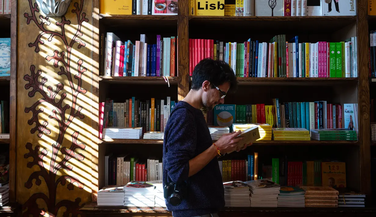 Seorang pria membaca buku di toko buku Lello, Porto, Portugal, Sabtu (12/1). Toko buku Lello ini kini tengah berada di ambang kebangkrutan. (MIGUEL RIOPA/AFP)