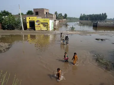 Orang-orang mengarungi banjir di Charsadda, Pakistan, Rabu (31/8/2022). Para pejabat di Pakistan menyampaikan kekhawatiran Rabu atas penyebaran penyakit yang ditularkan melalui air di antara ribuan korban banjir saat air banjir dari hujan monsun yang kuat mulai surut di banyak bagian negara. (AP Photo/Mohammad Sajjad)