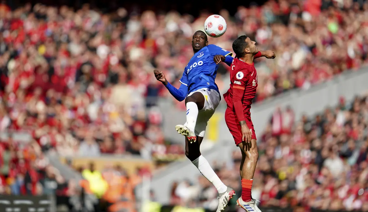 <p>Gelandang Liverpool, Thiago berebut bola udara dengan pemain Everton, Abdoulaye Doucoure selama pertandingan pertandingan lanjutan Liga Inggris di stadion Anfield di Liverpool, Inggris, Minggu (24/4/2022). Liverpool menang atas Everton dengan skor 2-0. (AP Photo/Jon Super)</p>