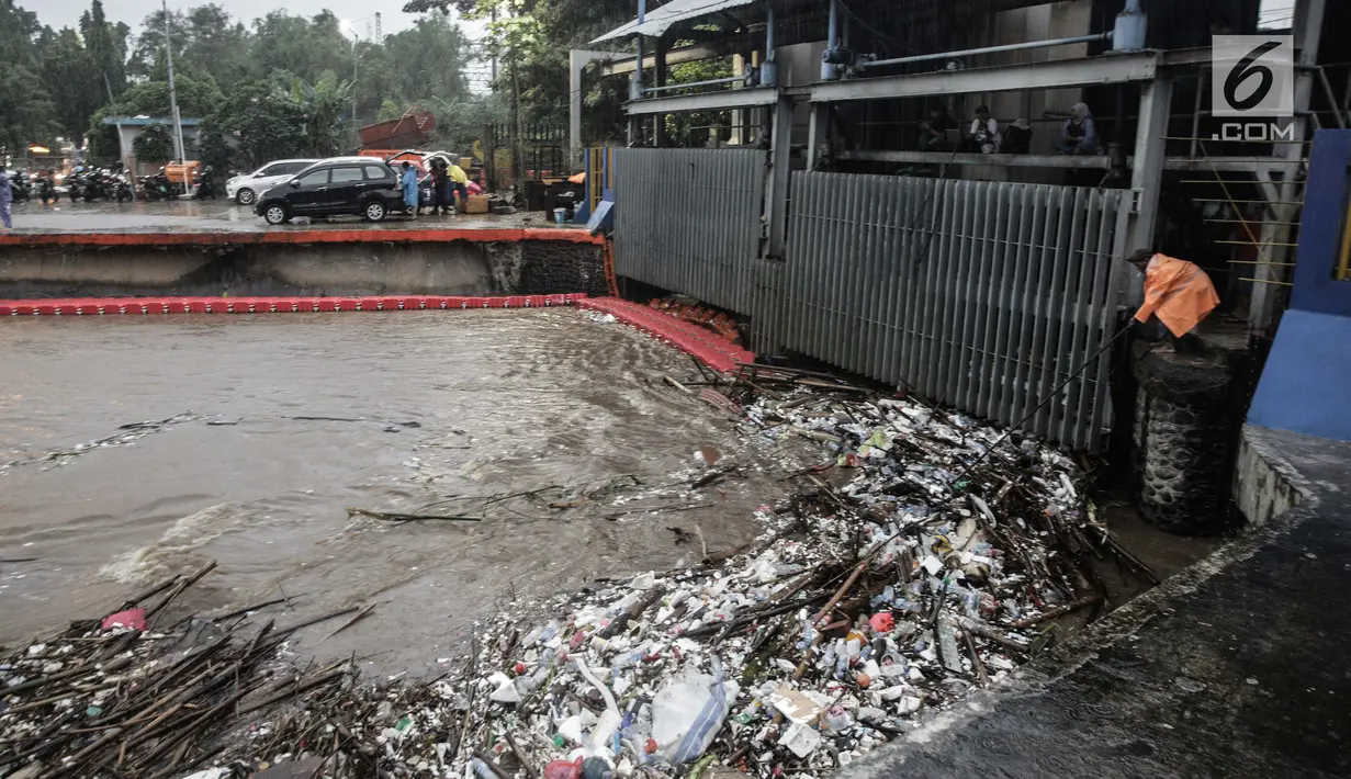 Seorang petugas membersihkan sampah yang menyangkut di Pintu Air Manggarai, Jakarta, Senin (5/2). Volume sampah terus meningkat lebih dari 200 ton. (Liputan6.com/Faizal Fanani)