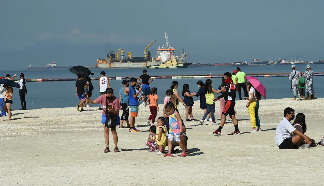 Orang-orang menikmati suasana Manila baywalk dolomite beach di sepanjang boulevard Roxas, kota Manila, Filipina pada Minggu (17/10/2021). Sehari sebelumnya, pihak berwenang melonggarkan pembatasan karantina di ibu kota negara itu. (Ted ALJIBE / AFP)