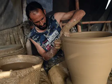Seorang pembuat tembikar membuat pot tanah liat di sebuah bengkel di Karachi, Pakistan, Rabu (23/2/2022). (Rizwan TABASSUM/AFP)