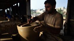 Seorang pembuat tembikar membuat pot tanah liat di sebuah bengkel di Karachi, Pakistan, Rabu (23/2/2022). (Rizwan TABASSUM/AFP)