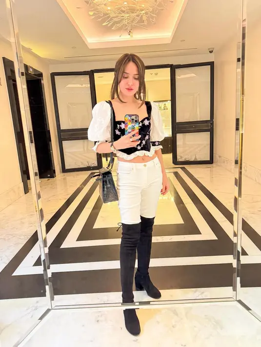 Ia mengenakan atasan sweetheart hitam putih dan skinny pants. Boots tinggi warna hitam jadi penutup sempurna. [@shandyaulia]