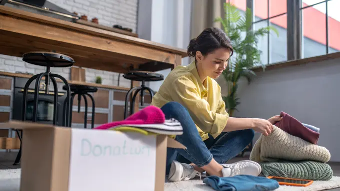 Seorang perempuan sedang memilah pakaian untuk didonasikan (Foto Dok: Freepik/zinkevych)