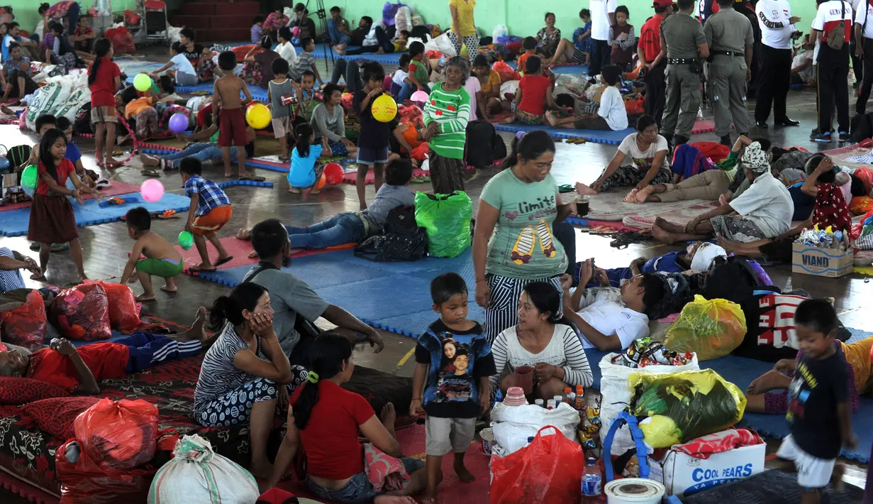 Penduduk desa beristirahat setelah dievakuasi di tempat penampungan sementara di Kabupaten Klungkung, Bali (22/9). Para penduduk desa dievakuasi sehubungan meningkatnya aktivitas Gunung Agung. (AFP Photo/Sonny Tumbelaka)