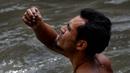 Seorang pria mengamati benda yang ditemukannya di saluran pembuangan limbah di Sungai Guaire, di Caracas, (1/2). Puluhan warga mencari logam atau tembaga setiap hari di Sungai Guaire. (AFP Photo/Federico Parra)