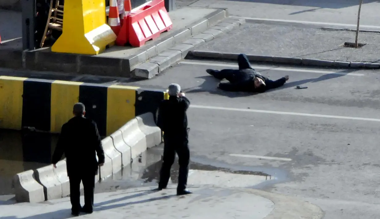 Polisi Turki mengarahkan senjata kepada seorang pria yang tergeletak di tanah, di luar kantor polisi di Gaziantep, Selasa (10/1). Pria itu ditembak mati, setelah sebelumnya mencoba memaksa masuk ke dalam kantor polisi dan menembak petugas. (AFP PHOTO/STR)
