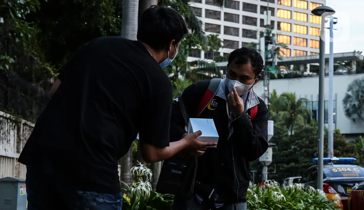 Pewarta Foto membagikan takjil kepada pejalan kaki di Kawasan Bundaran HI, Jakarta, Selasa (20/4/2021). Kegiatan berbagi takjil yang digagas oleh Pewarta Foto Indonesia Jakarta (PFIJ) ini dilaksanakan setiap hSelasa dan Jumat selama bulan Ramadhan sebagai bentuk solidaritas (Liputan6.com/JohanTallo)