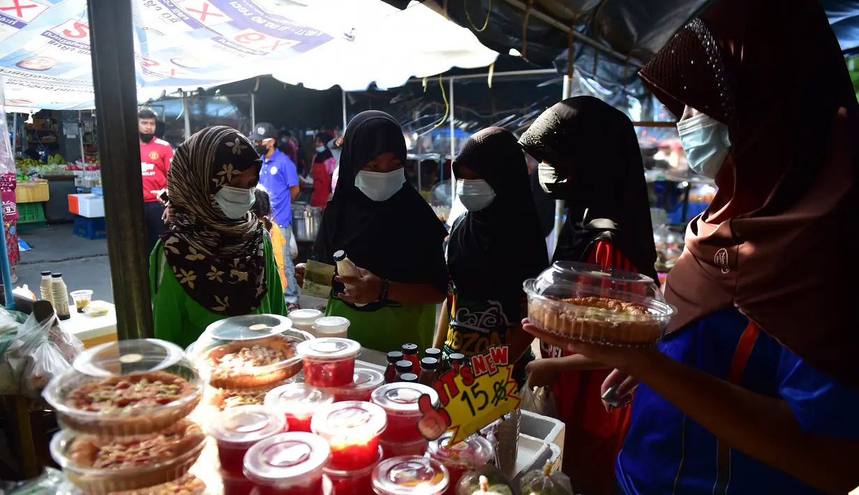 Sejumlah wanita mengenakan masker di pasar, sebagai bagian dari upaya untuk menghentikan penyebaran virus corona Covid-19, selama bulan suci Ramadhan di provinsi selatan Thailand, Narathiwat (17/4/2021). (AFP/Madaree Tohlala)
