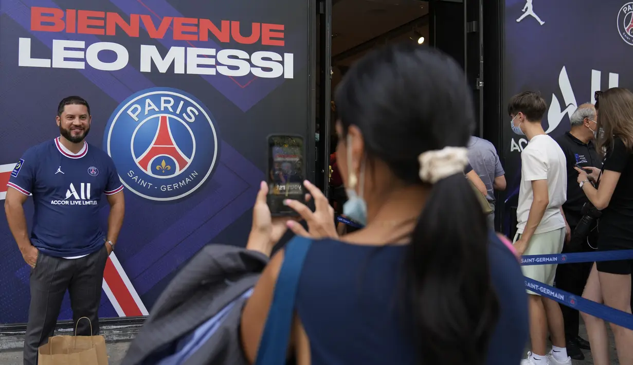 Turis AS Nancy Cornejo mengambil foto temannya Argilio Rodriguez dari New York yang mengenakan jersey bertuliskan nama Lionel Messi di luar toko resmi PSG di Paris, Rabu (11/8/2021). Penjualan jersey PSG dengan nama Messi dan nomor punggung 30 laris manis. (AP Photo/Francois Mori)