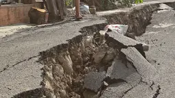 Seorang anak berdiri dekat ruas jalan yang ambles di Jalan Kesatria, Matraman, Jakarta, Selasa (3/3/2020). Hujan lebat yang mengguyur Ibu Kota beberapa waktu lalu mengakibatkan ruas jalan sepanjang 100 meter di kawasan tersebut retak dan ambles. (Liputan6.com/Herman Zakharia)