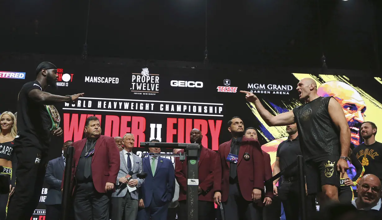 Petinju asal Inggris, Tyson Fury (kanan) menunjuk ke arah Deontay Wilder dari AS saat melakukan penimbangan berat badan untuk pertandingan tinju kelas berat WBC di Las Vegas (21/2/2020).  Tyson Fury dan Deontay Wilder akan bertanding di MGM Arena. (AP Photo/Isaac Brekken)