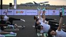 Sebagian besar dari mereka mengenakan seragam yoga berupa legging hitam dan kaos putih berpotongan pendek - dalam hal ini bertuliskan kata "BREW" untuk Brew Yoga yang menyelenggarakan acara tersebut. (MANAN VATSYAYANA / AFP)