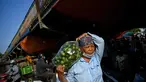 Seorang wanita membawa sekantong jeruk di pasar grosir di Hanoi (26/8/2020). (AFP Photo/Manan Vatsyayana)