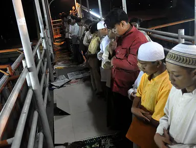 Puluhan warga melaksanakan ibadah Salat Tarawih pertama di kawasan Pasar Gembrong, Jakarta, Rabu (17/6/2015). Terbatasnya jumlah daya tampung musholla membuat warga terpaksa salat di jembatan. (Liputan6.com/Johan Tallo)