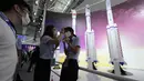 Seorang pekerja merias wajah rekanya di dekat replika roket peluncuran luar angkasa yang diproduksi China Aerospace Science and Technology Corporation yang menangani program luar angkasa China selama Airshow China 2021 di Zhuhai di provinsi Guangdong, China (38/9/2021). (AP Photo/Ng Han Guan)