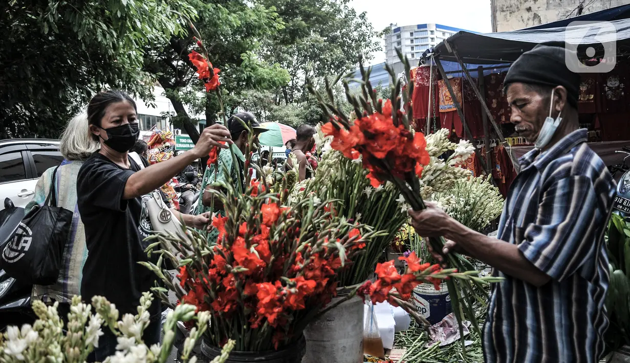 Pedagang menata bunga hias dagangannya saat menunggu pembeli di Pasar Petak Sembilan, Jakarta, Kamis (11/2/2021). Bunga hias yang dijual antara lain sedap malam, anggrek, krisan, dan lotus. (merdeka.com/Iqbal S. Nugroho)