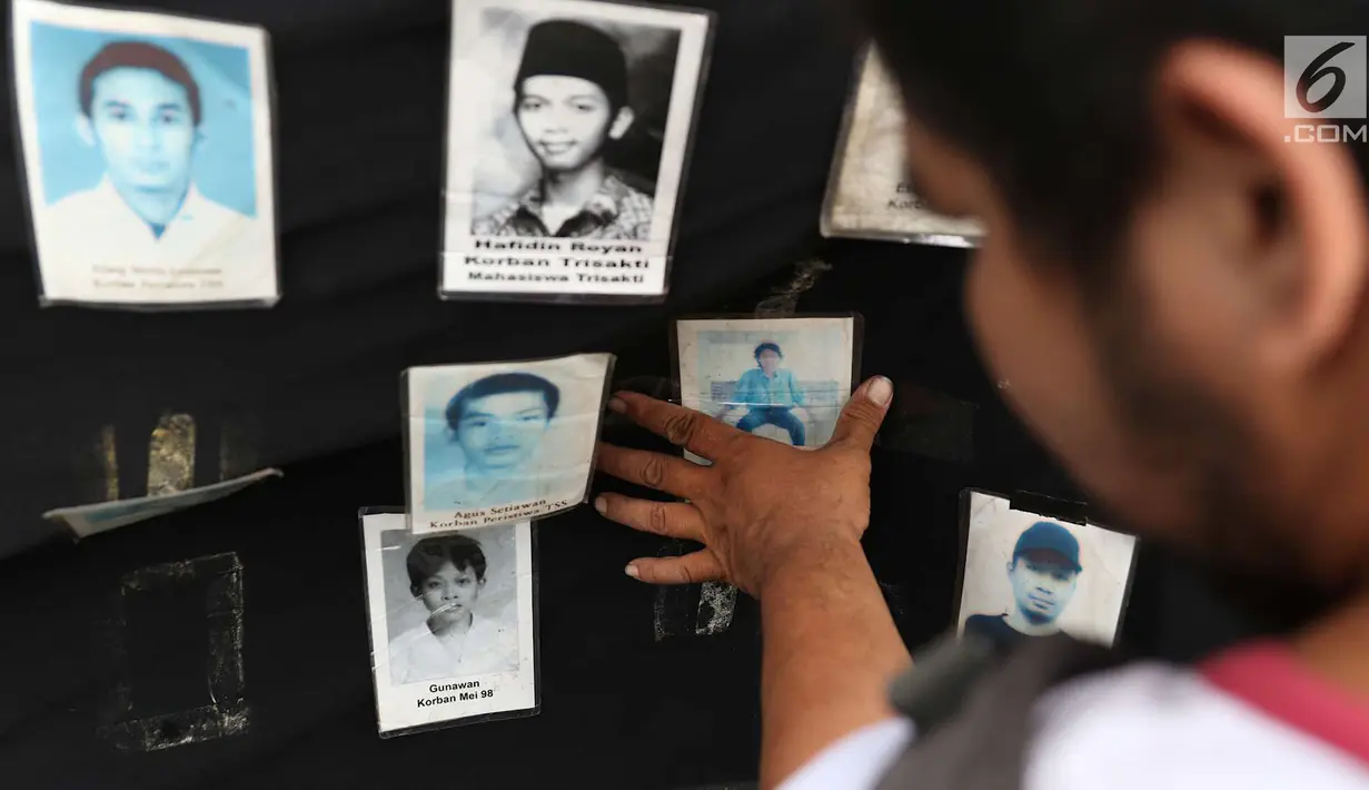 Aktivis melihat foto para korban HAM saat aksi Kamisan ke-538 di depan Istana Negara, Jakarta, Kamis (17/5). Aksi Kamisan tersebut sekaligus memeringati 20 tahun reformasi. (Liputan6.com/Immanuel Antonius)