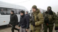 Tawanan perang asal Ukraina dikawal tentara-tentara kelompok separatis dukungan Rusia, berjalan ke bus-bus untuk proses pertukaran tahanan di Horlivka, timur Ukraina, 29 Desember 2019. (AP)