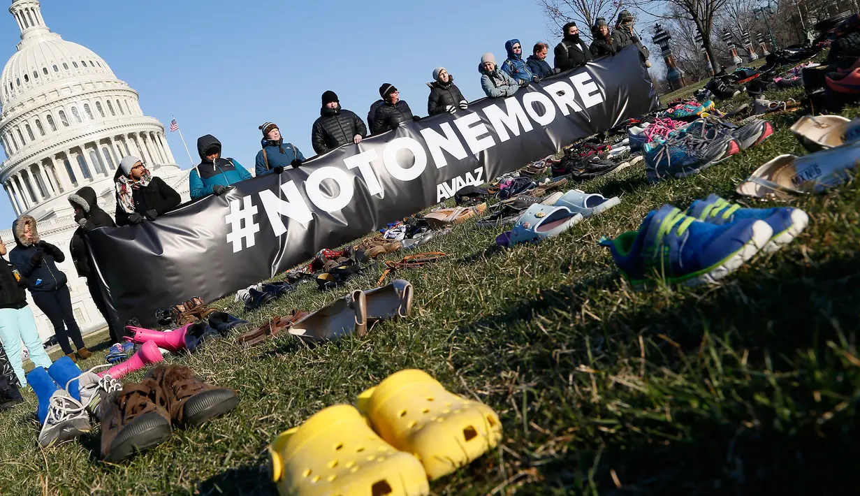 Spanduk #NOTONEMORE dibentangkan di antara ribuan sepatu yang menutupi halaman rumput di depan Gedung Capitol, Selasa (13/3). Spanduk tersebut sebagai pesan agar tidak ada lagi korban anak-anak dari penembakan di AS. (Paul Morigi/AP Images for AVAAZ)