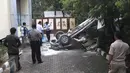 Petugas saat akan menutupi sebuah mobil Toyota Kijang warna merah marun yang jatuh dari lantai 3 Gedung Migas, Jakarta, Selasa (5/4). Mobil itu menabrak dinding pembatas di lantai 3 dan kemudian jatuh terbalik. (Liputan6.com/Helmi Affandi)
